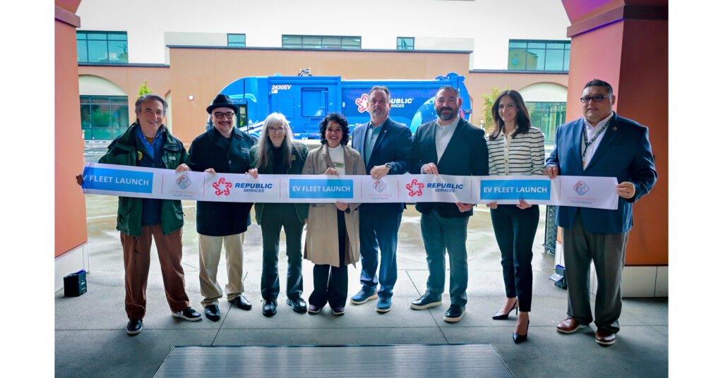Eight people holding blue ribbon at electric waste collection vehicle launch ceremony