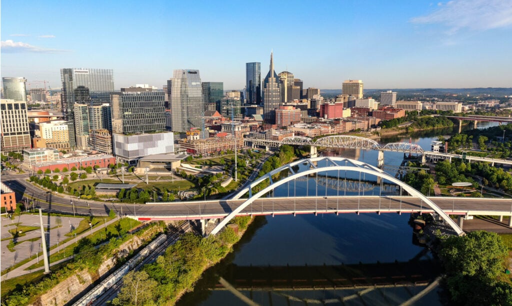 Aerial view of urban skyline with modern arch bridge spanning river and downtown buildings