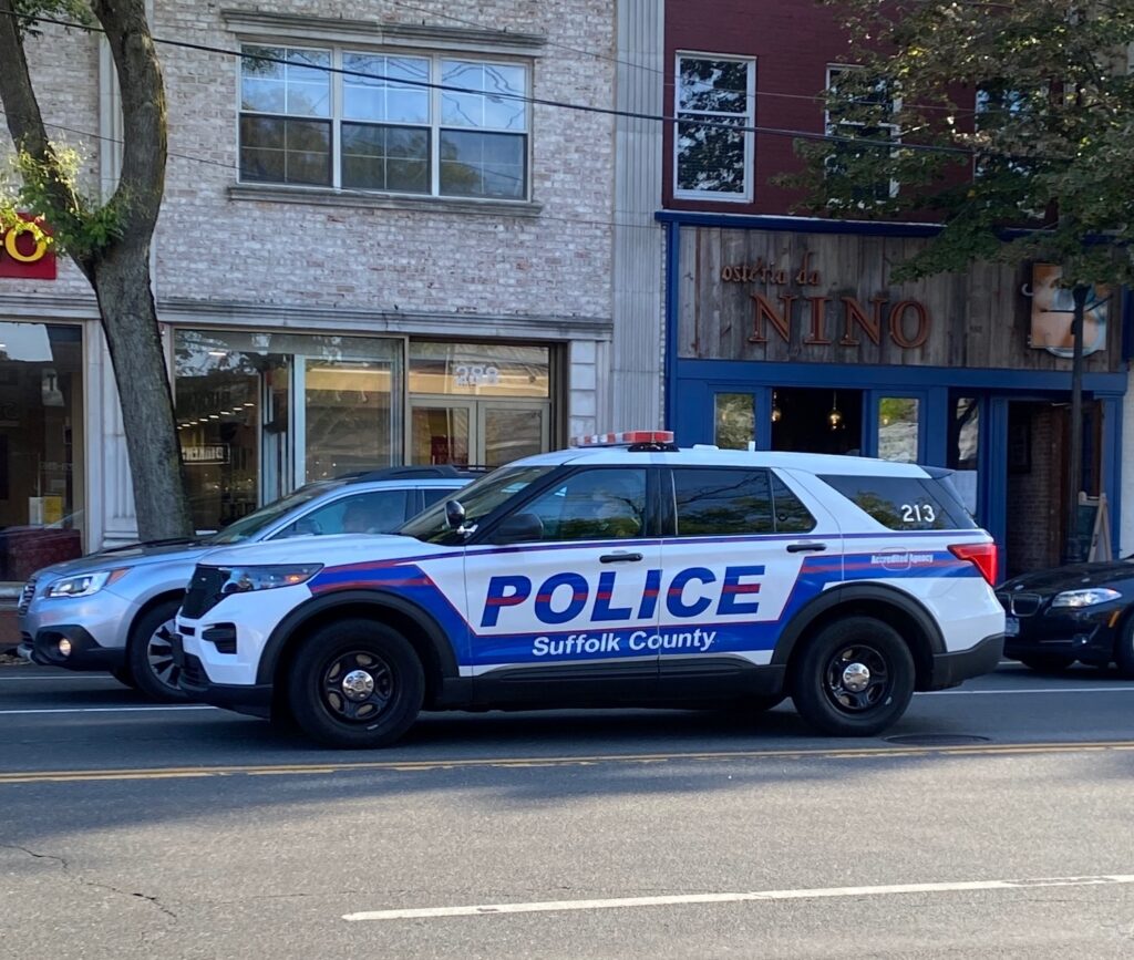 Suffolk County Police SUV parked on street in front of storefronts