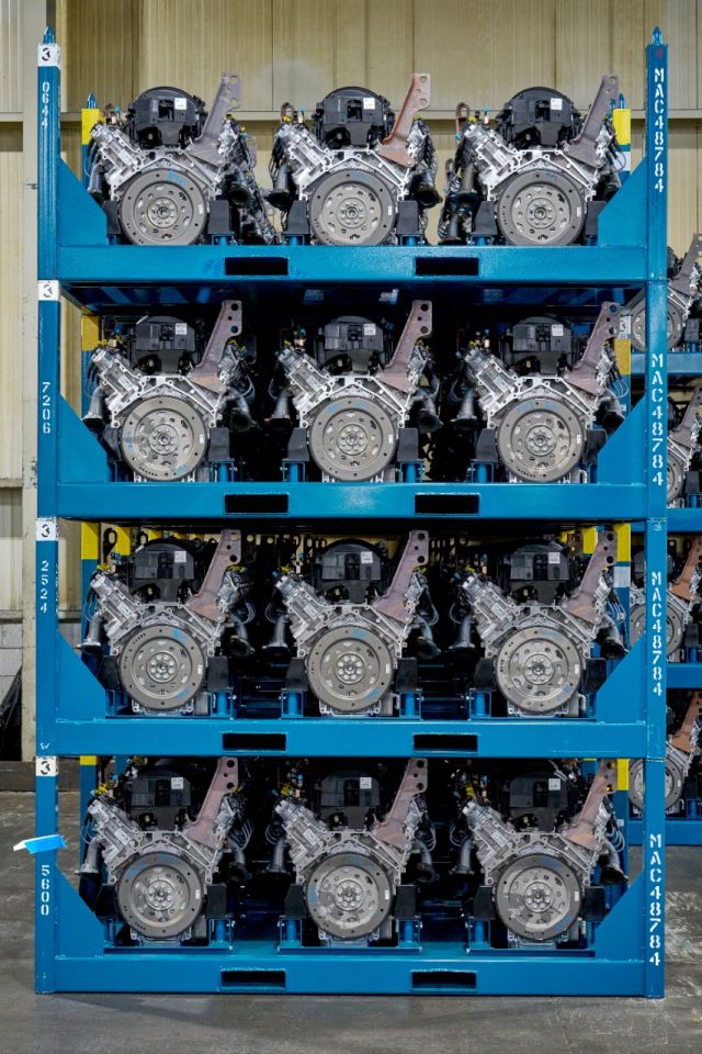 Four blue shelving racks displaying assembled automotive engines in an industrial warehouse setting