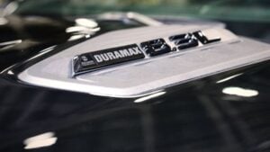 Close-up of Duramax badge on truck hood, chrome emblem on white surface