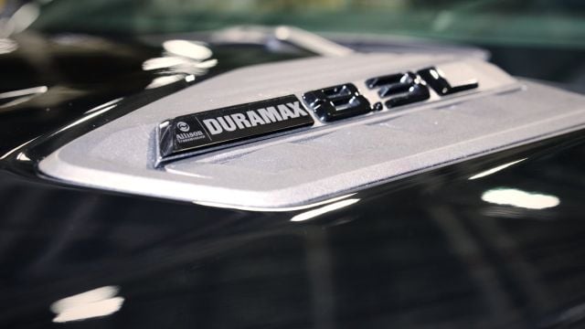 Close-up of Duramax badge on truck hood, chrome emblem on white surface
