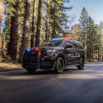 Black Ford Police Expedition driving on forest road with lights activated