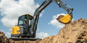 John Deere compact excavator with yellow bucket digging in earthen pit