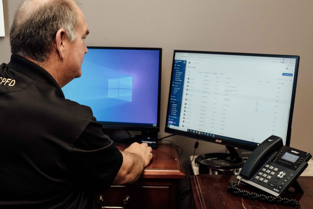 Fleetio Fleet staffer reviewing a list of vehicle service records on a desktop monitor