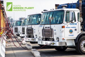 Row of white municipal utility trucks lined up at charging station with NAFA Green Fleet Awards logo
