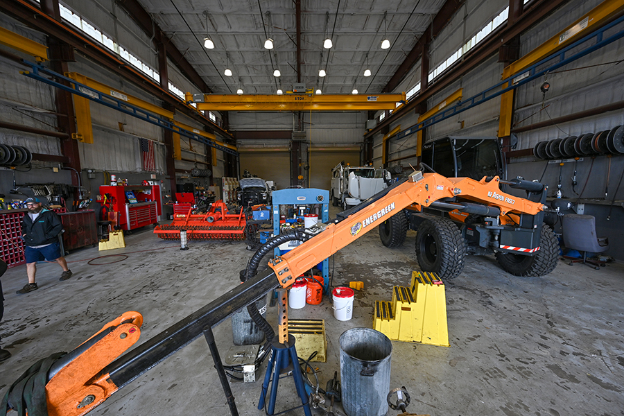 Industrial warehouse with orange telescopic handler, maintenance equipment, and tool storage