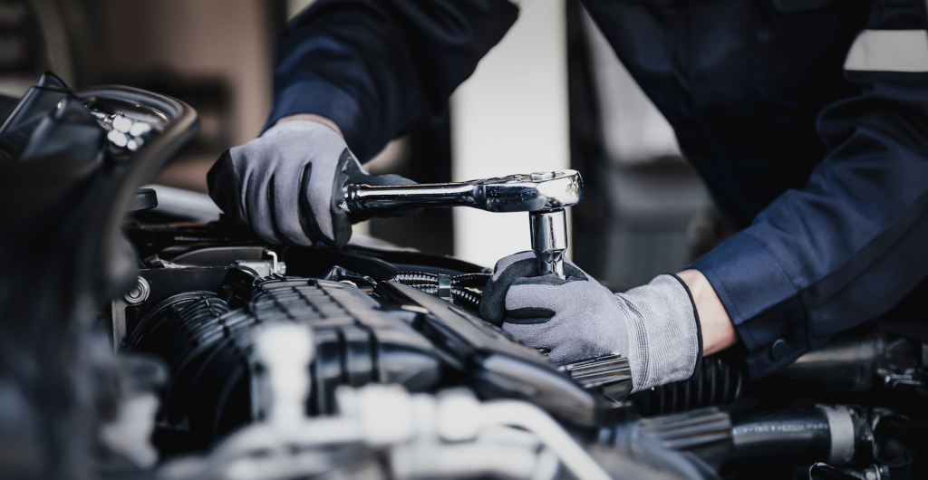Technician in work gloves performing engine maintenance on vehicle component