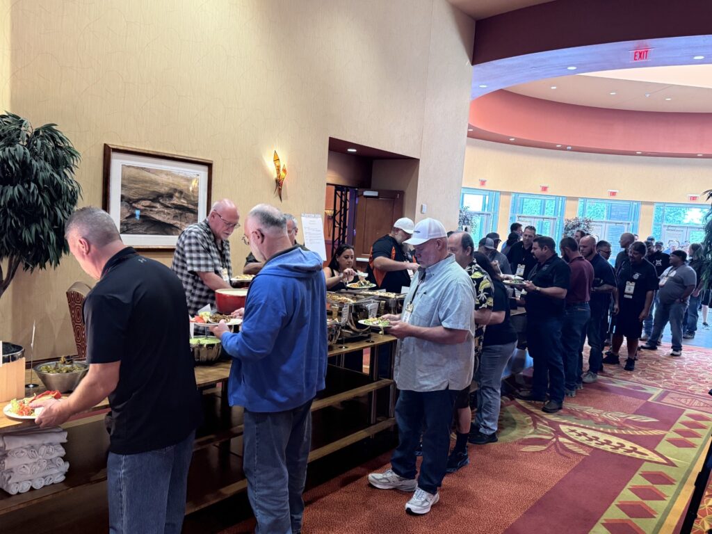 Large group of people standing in line at an indoor buffet-style food service event
