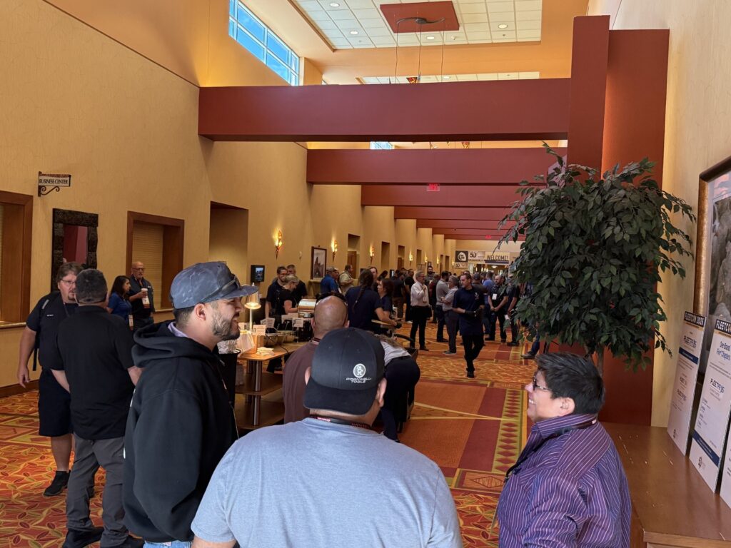 Attendees networking in a convention center hallway with yellow walls and burgundy architectural elements