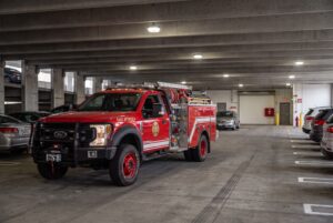 Red fire engine parked in underground garage with civilian vehicles nearby
