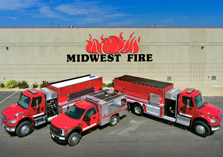 Three red fire trucks parked in front of Midwest Fire building