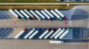 Aerial view of semi trucks parked in angled rows at a distribution or staging facility