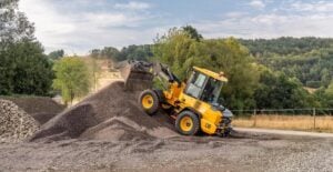 Yellow wheel loader dumping gravel onto stockpile at quarry or construction site