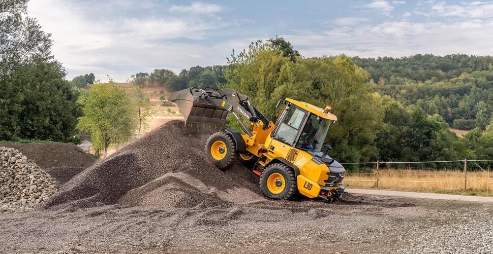 Yellow wheel loader dumping gravel onto stockpile at quarry or construction site