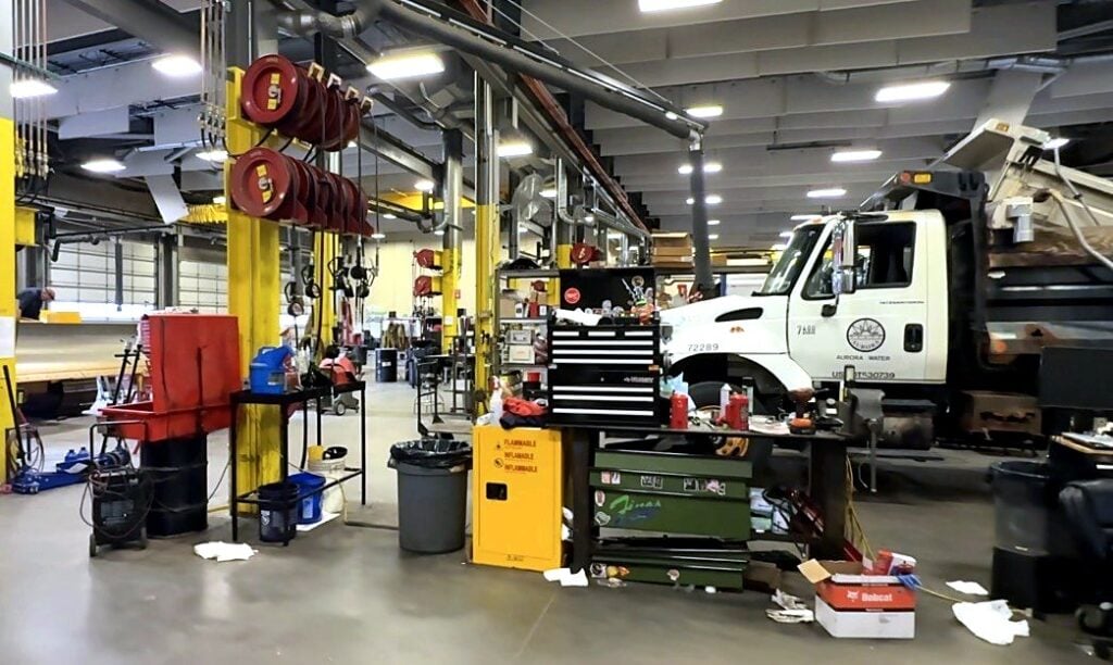 An Aurora Water dump truck in a heavy-duty bay with hose reels and toolboxes at the City of Aurora fleet shop