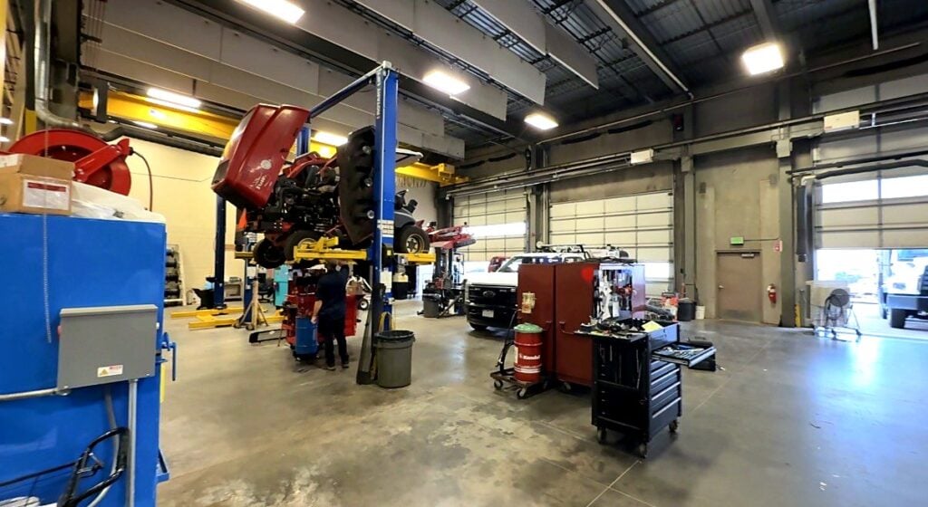 A technician works under a mower raised on a lift at the City of Aurora fleet shop