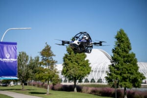 Tethered drone hovering above grassy campus area with Florida Poly banner visible