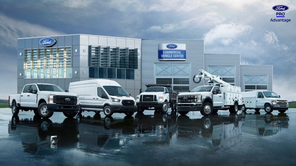 Ford Pro Commercial Vehicle Center with white pickup trucks and service vehicles reflected in wet pavement