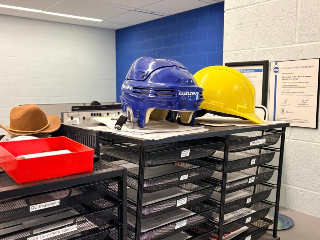 Blue and yellow hard hats displayed on shelf with safety equipment and certificates