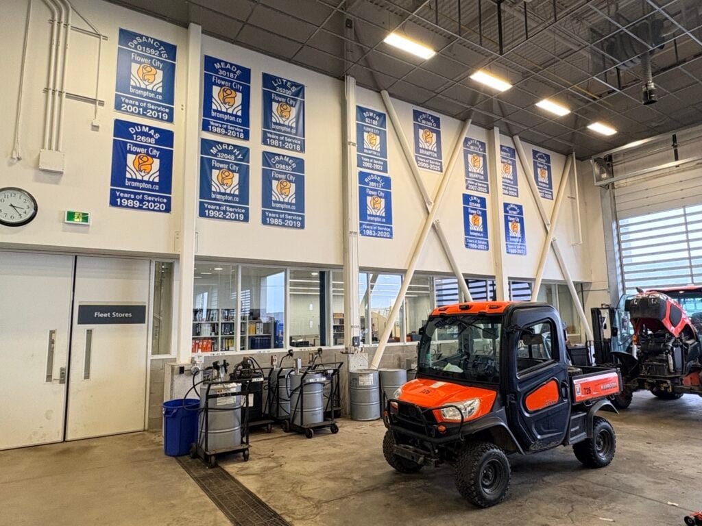 Interior of fleet maintenance facility with orange utility vehicle and championship banners on wall