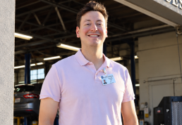 Man in light purple polo shirt standing in industrial warehouse setting