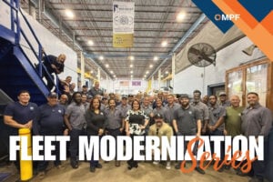 Large group of fleet workers posing together in industrial warehouse facility with MPF logo visible