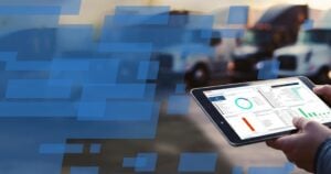 Hand holding tablet displaying fleet analytics dashboard with charts and performance metrics outdoors