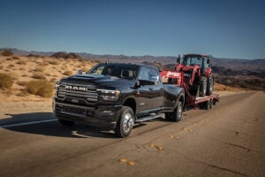 Ram heavy-duty pickup truck towing red equipment trailer on desert road