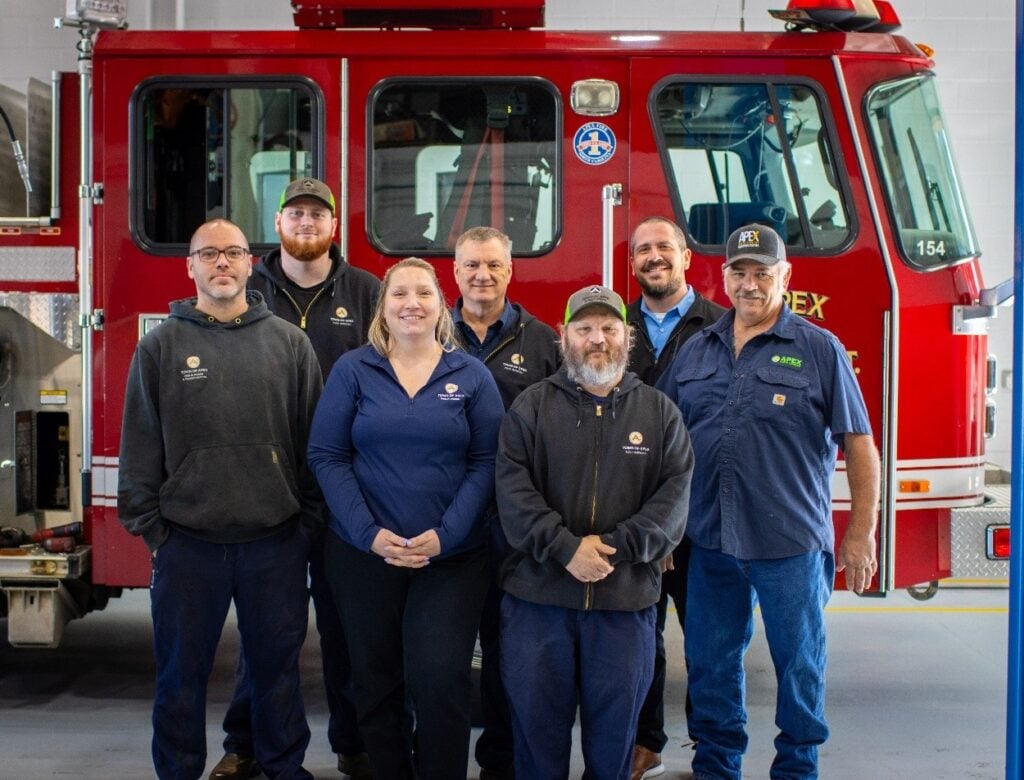 Town of Apex fleet services team standing in front of a fire engine in the shop