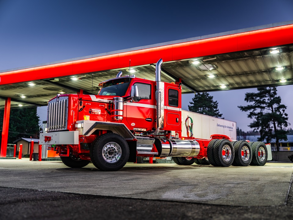 Red semi-truck parked under red canopy structure at commercial facility