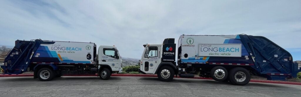 Two City of Long Beach electric refuse trucks parked on a hilltop road