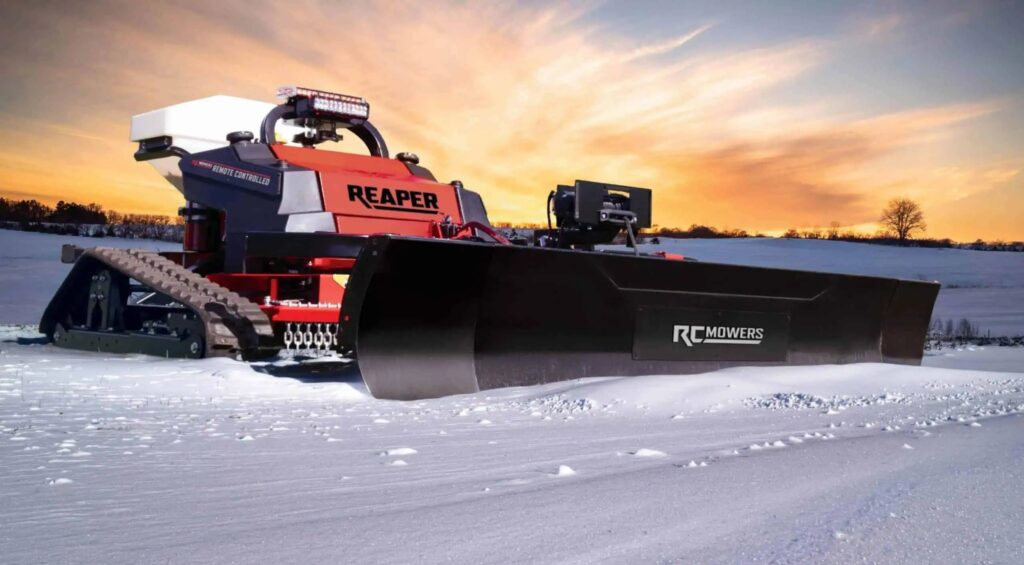 RC Mowers REAPER remote-controlled slope mower fitted with a snowplow in snow at sunset