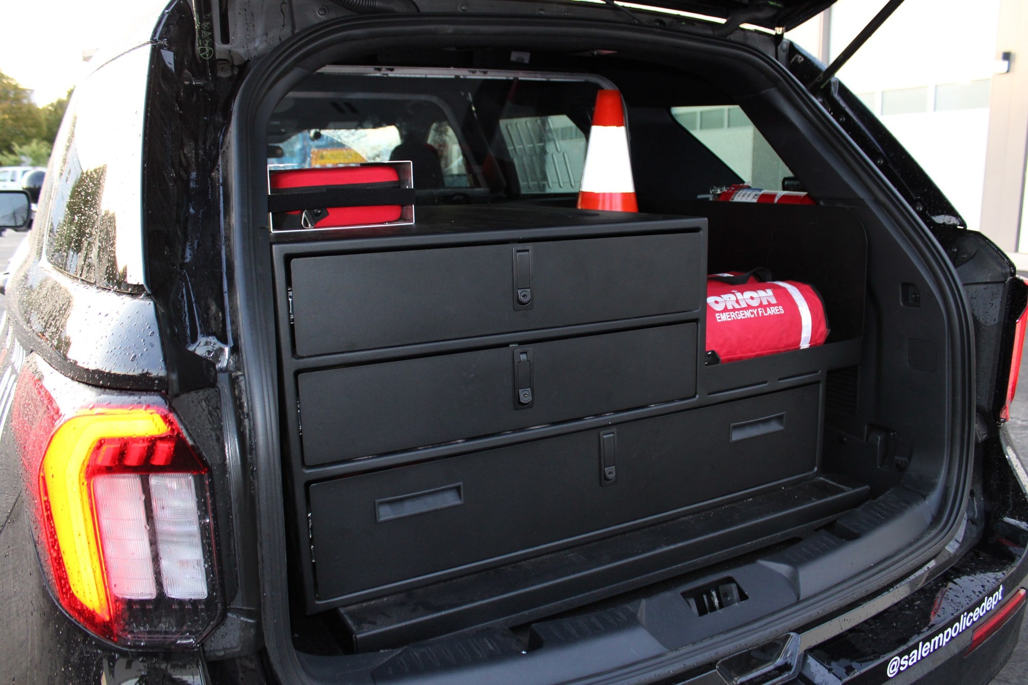 Locking storage drawers, a traffic cone, flares and a first aid kit in the cargo area of a Salem patrol vehicle