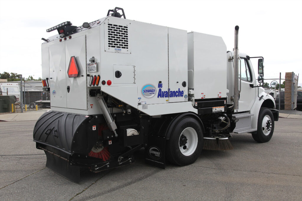 White Avalanche brand street sweeper truck with black brush attachment, parked in lot