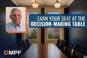 Man in blue shirt beside conference table with text "Earn Your Seat at the Decision-Making Table" and MPF logo
